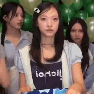 a group of young women are standing around a table with balloons .