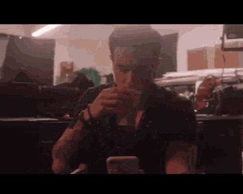 a man is drinking from a plastic cup while looking at his phone .