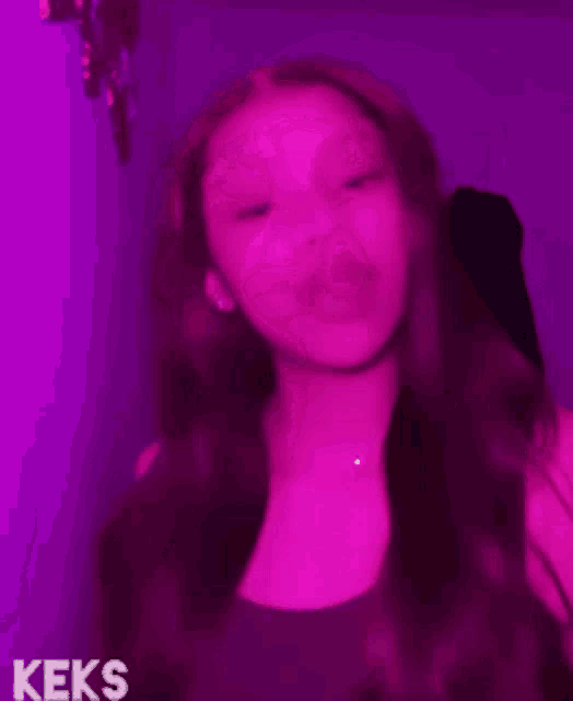 a woman is standing in front of a purple wall with the word keks on the bottom right