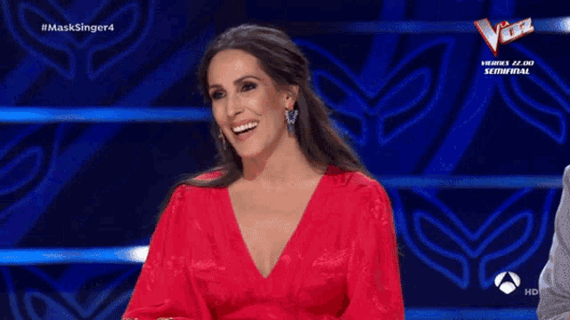 a woman in a red dress is smiling in front of a blue background that says #masksinger4