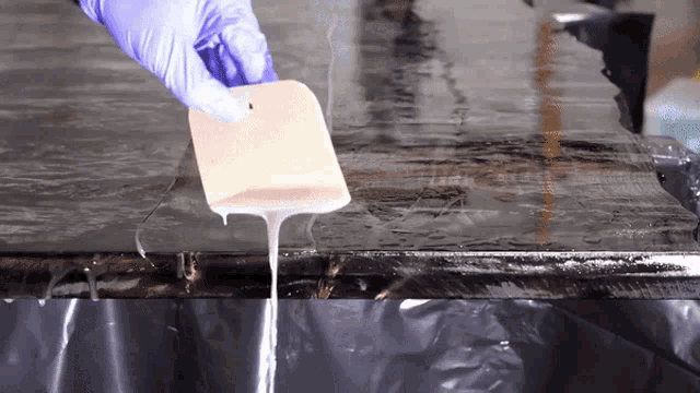 a person wearing purple gloves is holding a sponge over a table