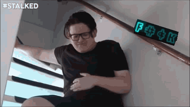 a man is sitting on a set of stairs next to a sign that says f + ck