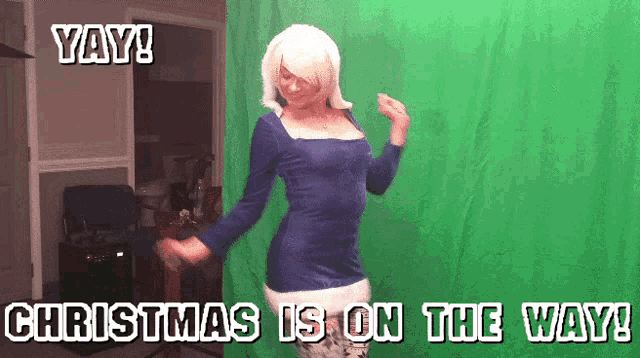 a woman in a blue dress is dancing in front of a green screen with the words yay christmas is on the way