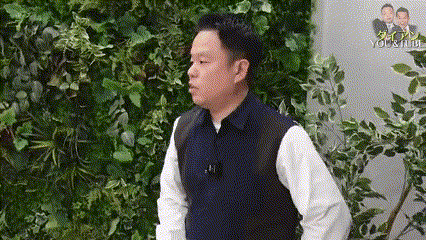 a man is standing in front of a wall of plants .