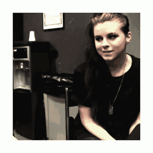 a woman with long hair is sitting in front of a water dispenser