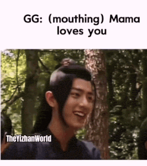 a man with long hair is smiling while standing in the woods with trees in the background .