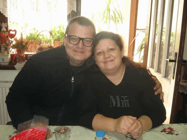 a man and a woman are posing for a picture and the woman is wearing a black shirt that says mm