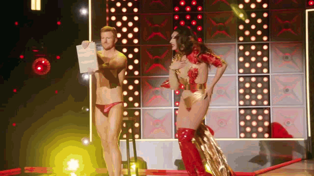 a man holding a piece of paper next to a woman in a red and gold outfit