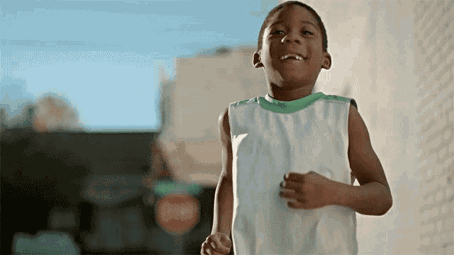 a young boy in a white shirt is running in front of a stop sign