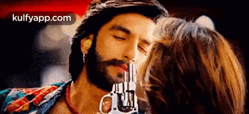 a man is kissing a woman on the cheek while holding a gun in his hand .