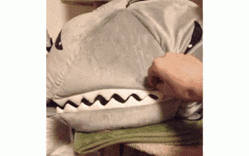 a person is holding a stuffed animal that looks like a shark 's head .