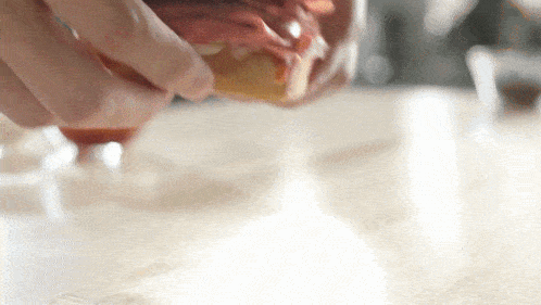 a person is pouring ketchup on a piece of meat on a table
