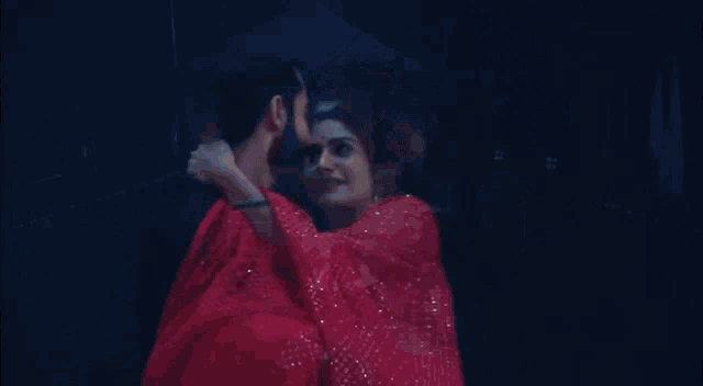 a man is carrying a woman in a red dress in his arms