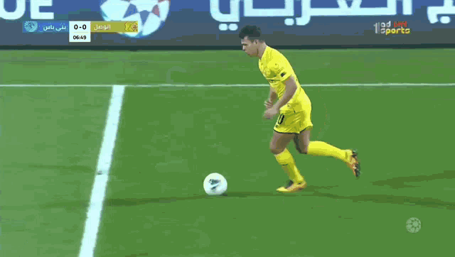 a man in a yellow jersey with the number 10 on it kicks a soccer ball on a field