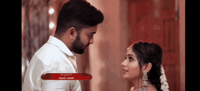 a man and a woman are looking into each other 's eyes with a red banner above them that says ' kannada '