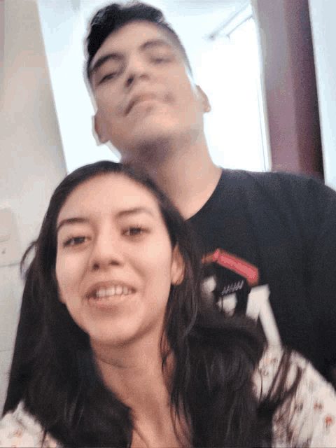 a man and a woman are posing for a picture and the man is wearing a shirt that says ' hawaii ' on it