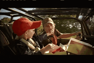 a man and a boy are sitting in a car and the boy is wearing a red hat with the letter t on it