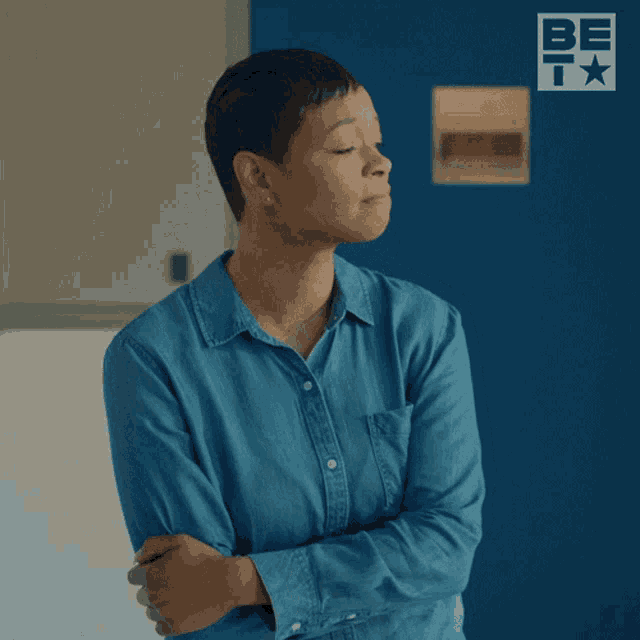 a woman in a blue shirt is making an alright gesture