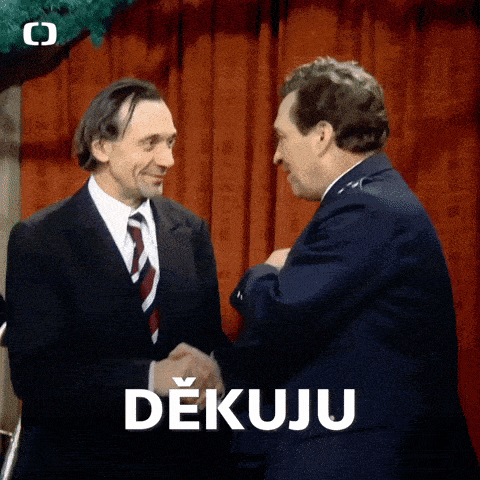 two men shaking hands in front of a red curtain and a sign that says dekuji