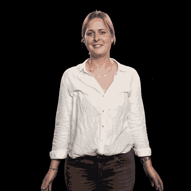 a woman wearing a white shirt and blue jeans is smiling with her arms outstretched