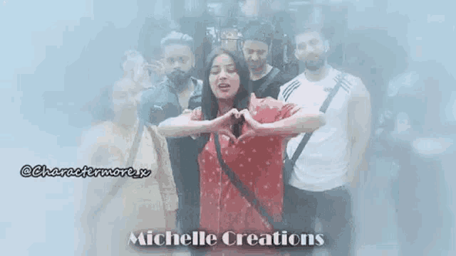 a group of people are standing next to each other and a woman is making a heart with her hands .