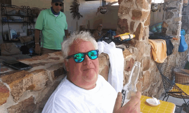 a man wearing sunglasses is sitting at a table with a bottle of water