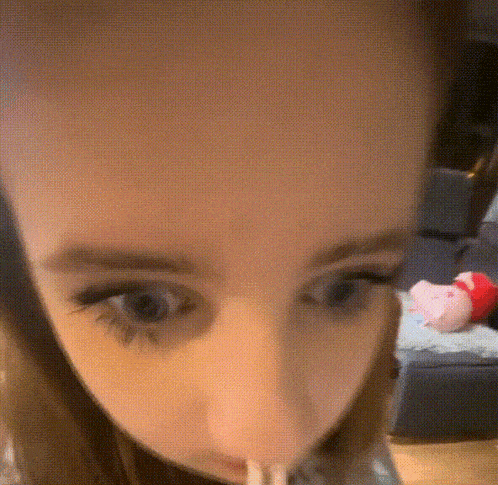 a close up of a woman 's face with a pink stuffed animal in the background