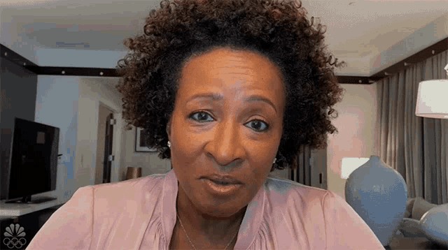 a woman with curly hair is wearing a pink shirt that says nbc