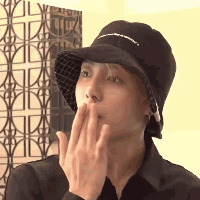 a young man wearing a black hat is blowing a kiss .
