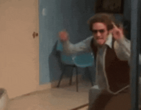 a man wearing sunglasses and a vest is standing in a hallway .