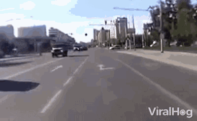 a car is driving down a street with a city in the background and the word viralhog on the bottom .