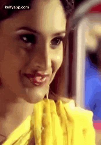 a close up of a woman 's face with a yellow shirt and red lips .