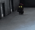 a black robot with yellow eyes is walking down a hallway in a dark room .