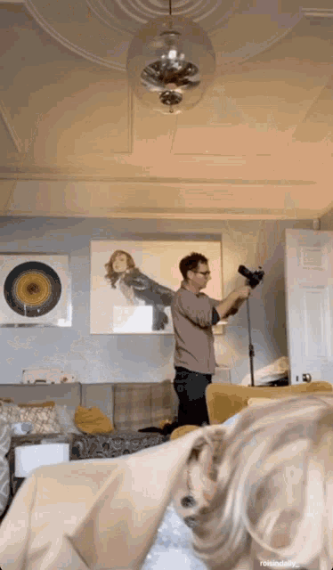 a man is taking a picture of a woman in a living room and the caption reads rewinddaily