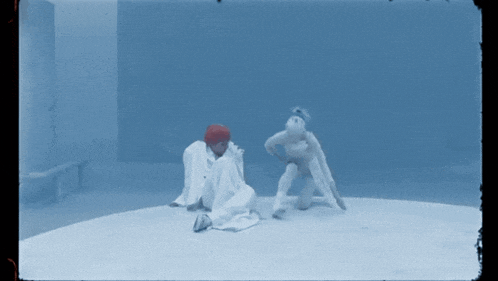 a man in a red hat is kneeling down next to another man in white