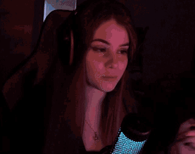 a young woman wearing headphones and a necklace looks at the camera