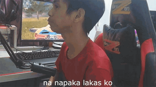 a man in a red shirt sits in front of a computer with the words na napaka lakas ko on the bottom right