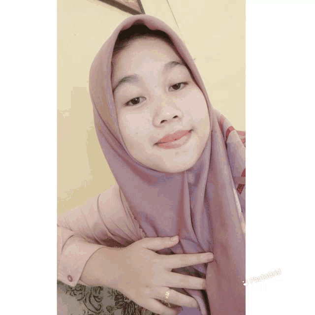 a woman wearing a purple scarf and a pink shirt is taking a selfie