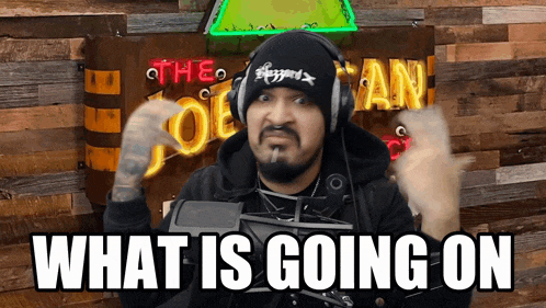 a man wearing headphones says " what is going on " in front of a wooden wall