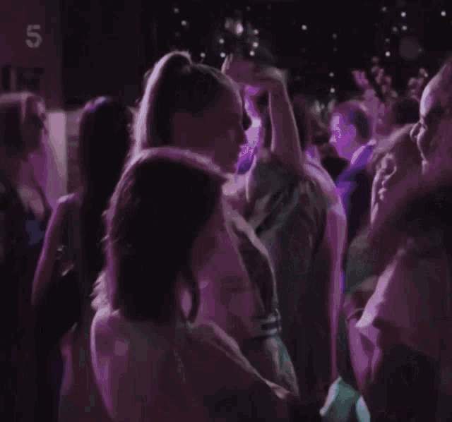 a group of people are dancing in a dark room with the number 5 on the bottom
