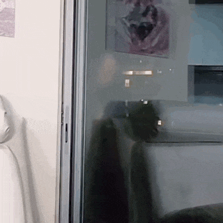 a person is standing in front of a glass door with a picture on the wall behind it .