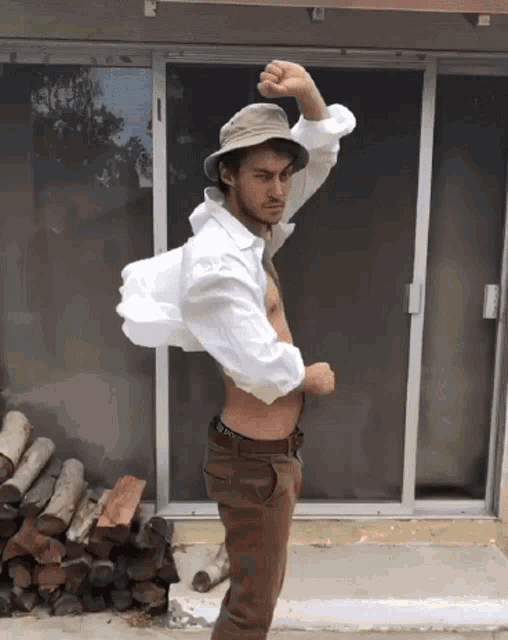 a man wearing a bucket hat and a white shirt is standing in front of a sliding glass door