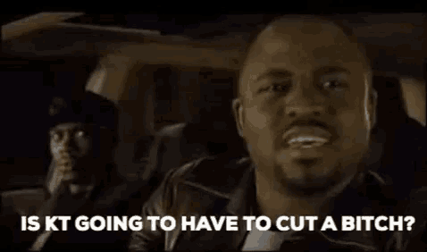 a man is sitting in the back seat of a car talking to another man while another man looks on .
