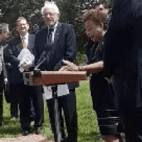 a group of people are standing around a podium talking to each other