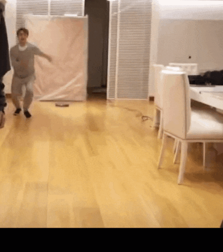a man is standing on a wooden floor in a room with chairs