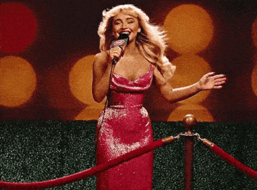 a woman in a red dress is singing into a microphone with a cbs logo on it