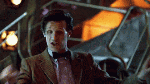 a man in a suit and bow tie is standing in a room with his arms outstretched