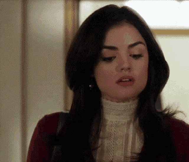 a woman with long dark hair is wearing a red sweater and a white top