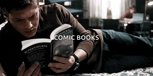 a man is laying on his stomach reading a comic book .
