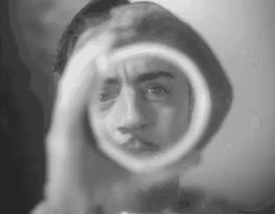 a black and white photo of a man looking at his face in a mirror .